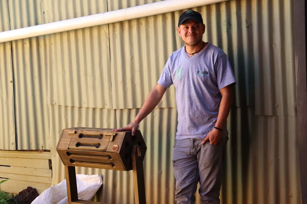 Joven mostrando una compostera como parte de un taller de gestión de residuos.