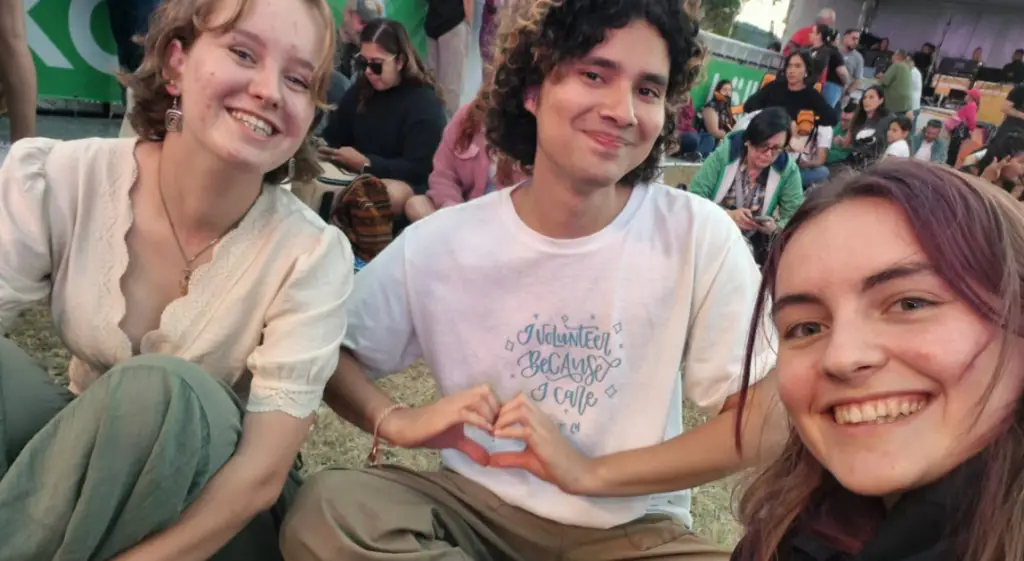 Aldo Membreño Brenes, leader of the Greentalist Orientation Commission, shares a heart-hand gesture with two fellow volunteers at an outdoor community event.