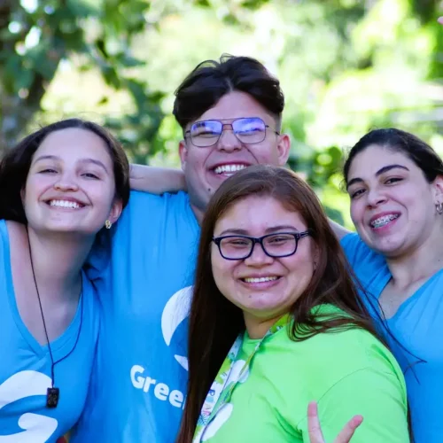 Jóvenes voluntarios sonriendo juntos en actividad ambiental.